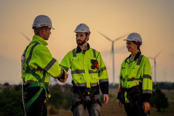 Team Engineers men and woman celebrating on construction site with sunset sky. people operation. Wind turbine for electrical of clean energy and environment. Industrial of sustainable.