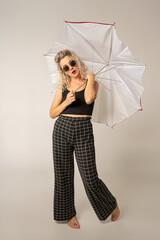 woman WITH WHITE CURLERS with an open umbrella over her head wearing a BLACK suit posing in PHOTO STUDIO