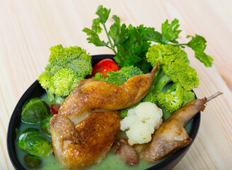 Tasty vegetable soup from Brussels sprouts, cauliflower, broccoli served with roasted quail and greens