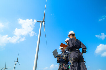 uprisen angle engineers working in fieldwork at outdoor with wind turbine and clear sky. Workers...