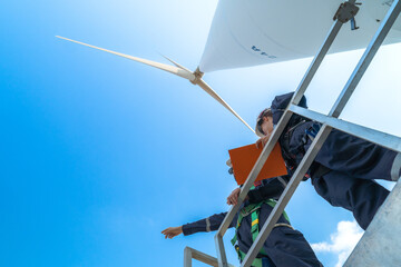 uprisen angle engineers working in fieldwork at outdoor with wind turbine and clear sky. Workers...