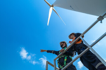 uprisen angle engineers working in fieldwork at outdoor with wind turbine and clear sky. Workers...