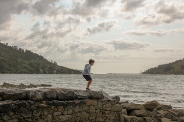 boy over a stone wall in a beach