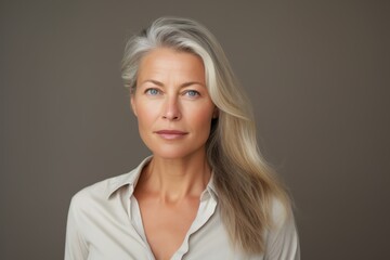 Portrait of a beautiful senior businesswoman with grey hair, over grey background.