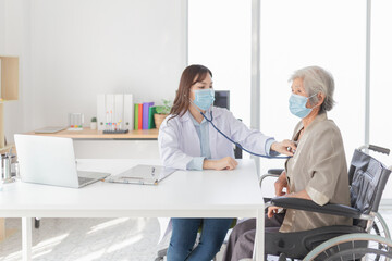 Obraz premium Asian doctor talk with old female patient about disease symptom, doctor use stethoscope listening lung of patient, elderly health check up , they wear surgical mask in hospital, corona virus 