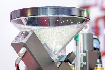 A transparent hopper with polypropylene granules is part of the injection molding machine. White...