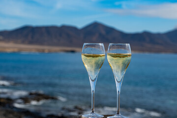 Pouring a glass of champagne on vacation, south of Fuerteventura, Canary islands, blue ocean, mountains