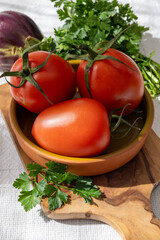 Ripe red Roma tomatoes in bowl with fresh herbs