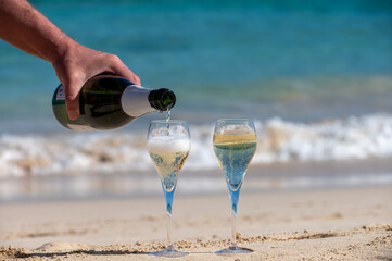 Obraz premium Pouring a glass of champagne on vacation, south of Fuerteventura, Canary islands, blue ocean, mountains