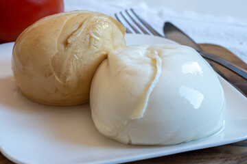 Tasty Italian food, small balls of white and smoked mozzarella soft cheese close up