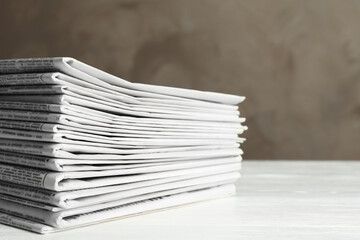 Stack of newspapers on white wooden table. Journalist's work