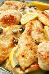 Delicious chicken piccata with lemons in pot, closeup
