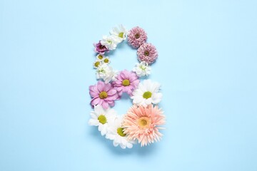 8 March greeting card design made with beautiful flowers on light blue background, top view