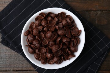 Chocolate corn flakes in bowl on wooden table, top view. Breakfast cereal