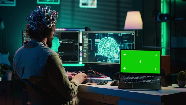 IT admin coding and using EEG headset to upload brain into green screen laptop, gaining immortality. Neuroscientist engineering transhumanism experiment on chroma key device, camera A