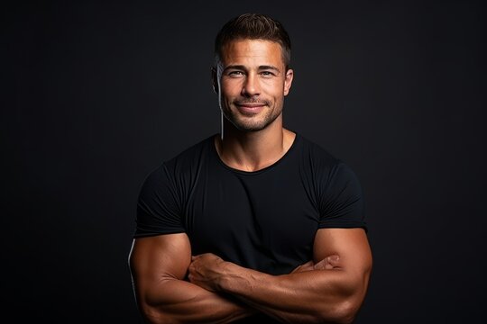 Portrait of a handsome young man with arms crossed on black background