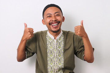 A smiling Indonesian Muslim man in koko and peci gives a thumbs-up gesture, expressing satisfaction or approval. Isolated on a white background