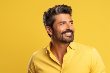 Handsome young man in yellow shirt looking up and smiling on yellow background