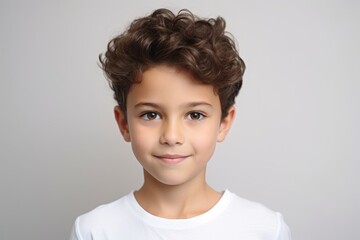 Portrait of a cute little boy with curly hair on a gray background
