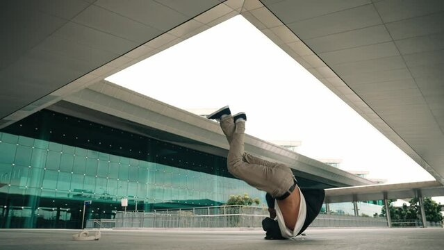 Happy hipster practice b boy dance with stylish cloth at building. Skilled street dancer enjoy show footstep performance. Modern lifestyle, break dancing. Slow motion. Outdoor sport 2024. Sprightly.