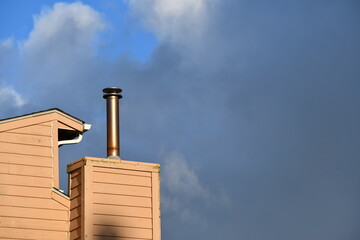 Metal chimney pipe against cloudy sky.