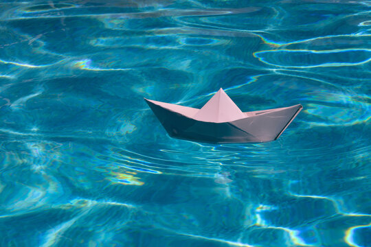 Origami ship. Paper ship sail. Paper boat on the sea water background. Dreaming traveling.