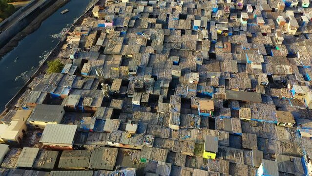 Aerial view tilting over the slums of Dharavi, sunny evening in Mumbai, India