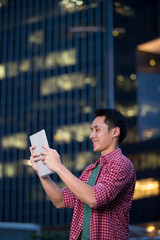 Asian man using his tablet in city at night...