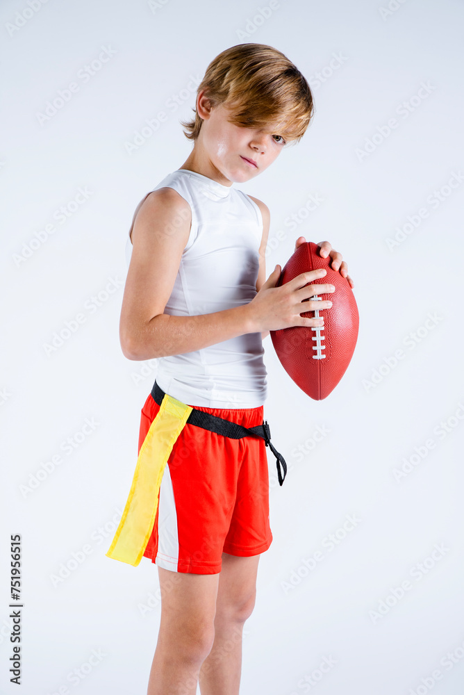 Wall mural Young male flag football player standing holding the ball