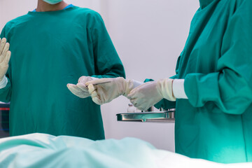 Assistant passing instrument to surgeon. Team of surgery doctor in Operating Room hold hands...
