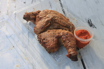 Indonesian dish called ayam bacem and sambal in plastic mica on the table