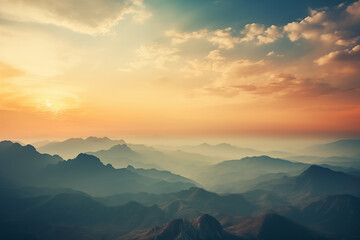 Sunset illuminating mountain range with clouds creating a dramatic atmosphere - obrazy, fototapety, plakaty