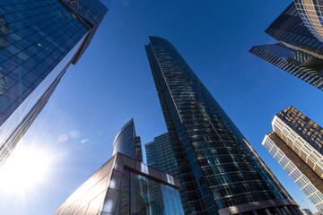 Fototapeta na wymiar Skyscrapers cover the blue sky in the city center. The bright sun in the sky.