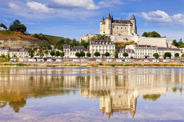 Saumur on the banks of the Loire River, Loire Valley, France. A long row of camper vans can be seen parked beside the river.