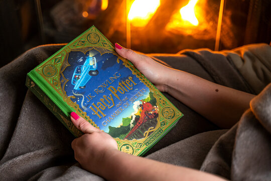 Teenage girl reading the second book about Harry Potter near the fireplace. "Harry Potter and the Chamber of Secrets"