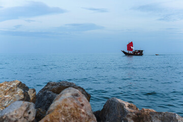 Obraz premium A ship with red sails sails on the sea after sunset