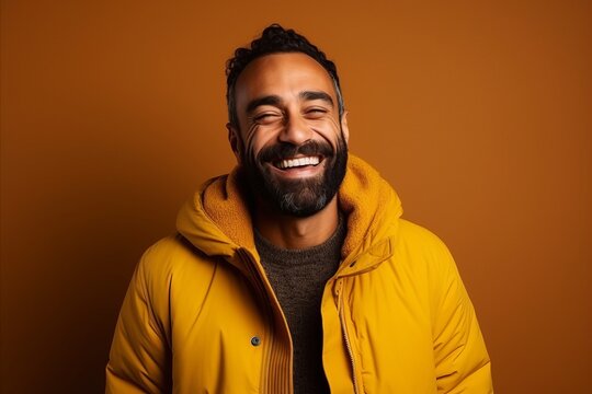 Portrait of a happy man laughing in a yellow jacket on a brown background