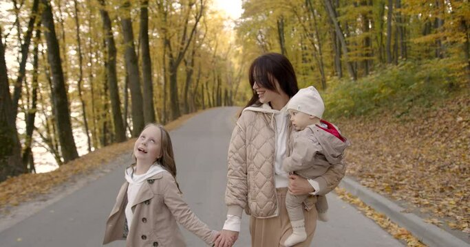 Young brunette woman walking with baby in autumn