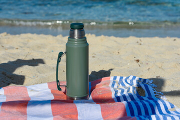Authentic green Stanley Thermos on the beach in summer