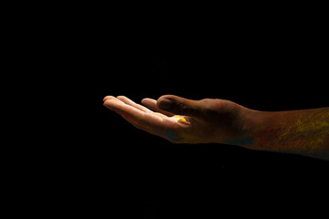 Close up hand covered with holi powder isolated over black background. Holi festival concept.