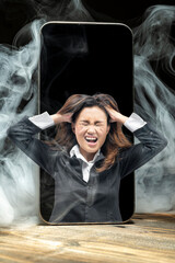 Close up smartphone with smokes and frsutated woman standing on a wooden desk.