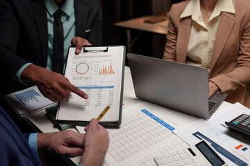 Confident group of business people pointing to graphs and charts to analyze market data, balance sheet, account, net profit, to plan sales strategy, startup business concept.