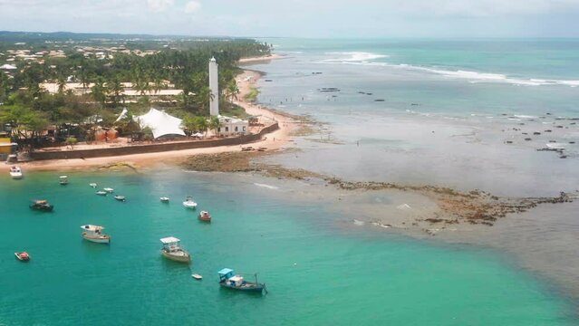 Aerial view of Praia do Forte beach, the coral reef, boats parked, palm tree area on a cloudy day, Praia do Forte, Bahia, Brazil