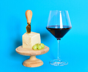 glas rotwein , parmesan käse und traube auf der glasglocke und dem bunten hintergrund
