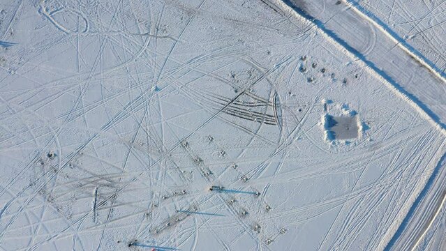 High aerial drone view filming straight down accross tracks of all kind in the white snow covering the frozen river in Berges-des-quatres-vents in Laval-Ouest
