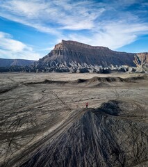 Person on cliff in front of eroded mountain with dirt bikes tracks. . Factory butte. Hanksville. Utah. USA