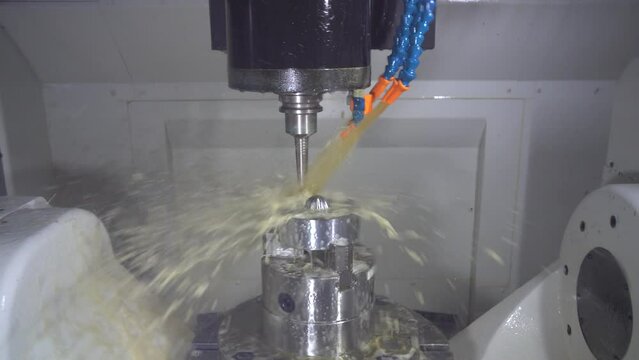 The 5-axis CNC milling machine  cutting the automotive part with oil coolant method.