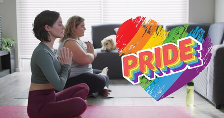 Image of rainbow heart and pride over lesbian couple practicing yoga at home