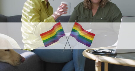 Image of rainbow flags over midsection of lesbian couple drinking coffee