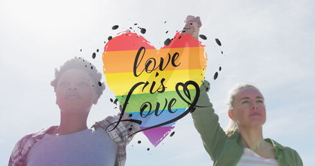 Image of rainbow heart and love is love over lesbian couple holding hands outdoors